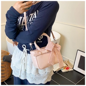 Detail of light pink square crossbody bag with lychee texture and a polka dot silk scarf
