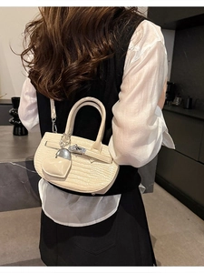Beige crocodile pattern handbag with metal lock and heart charm shown on a model