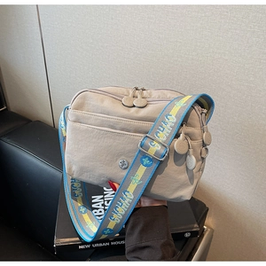 Détail du sac bandoulière en nylon kaki avec large sangle colorée et poches zippées
