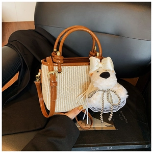 Détail d'un sac Boston en paille avec bordure en cuir et pendentif ours sur un siège