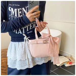 Detail of pink PU leather handbag featuring a silk scarf bow and decorative metal buckle