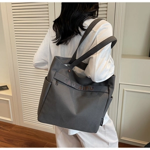 Detail of gray canvas tote bag featuring branded label and side pocket design
