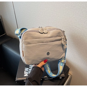 Détail du sac bandoulière gris à zips multiples avec sangle colorée et texture étanche