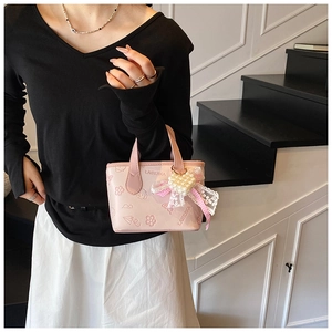 Close-up of pink mini bucket bag with embossed patterns and pearl heart charm detail