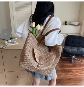 Close-up of woven straw tote bag with brown leather straps and summer tulip detail