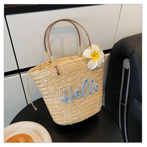 Detail der Strohtasche mit Hello-Stickerei, Kunst-Frangipani und schmalen Tragegriffen