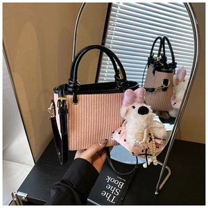 Sac seau tissé rose avec poignées noires et breloque chien en peluche dans un reflet de miroir