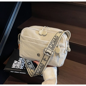 Détail de la bandoulière large à motifs de ce sac à main urbain beige en nylon texturé
