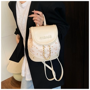 Detail of cream mini backpack featuring cartoon bear print and decorative gold chain