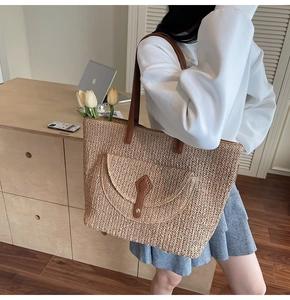 Detail of woven straw tote bag featuring leather shoulder straps and front flap pocket