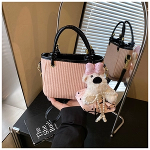 Détail du sac seau tissé rose avec bordure en cuir noir et breloque ours en peluche