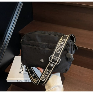 Détail du sac bandoulière noir en nylon avec multi-zips et large sangle à logo