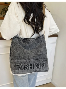 Retro washed denim tote bag with FASHION embroidery and brown strap shown on a model