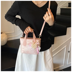 Pink PU bucket bag with floral prints and a pearl heart charm shown on a shoulder
