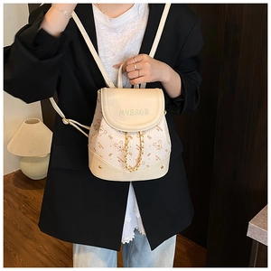 Close-up of cream leather mini backpack with bear print and gold chain decoration