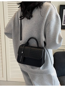 Chic black crossbody bag with woven texture and top handle shown on a model