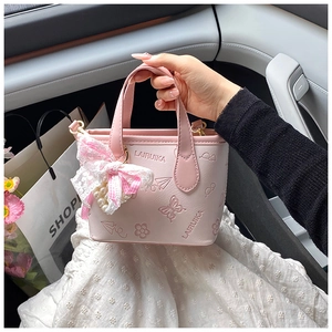Detail of pink PU leather bucket bag with butterfly embossing and pearl lace bow charm