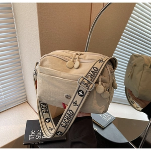 Vue détaillée du sac bandoulière beige multi-poches avec large bandoulière à motifs