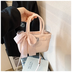 Close-up of pink leather handbag with decorative polka dot scarf and metal buckle