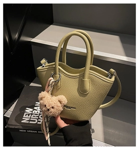 Détail du sac seau en cuir vert pistache avec breloque ours et finitions métalliques argentées