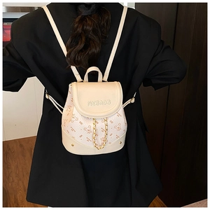 Detail view of cream mini backpack with bear prints and elegant gold chain strap