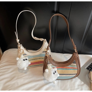 Close-up of rainbow woven half-moon bags with leather trim and plush monster charms