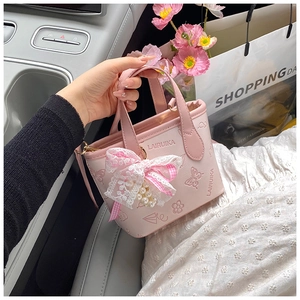 Detailed macro view of pink butterfly embossed bucket bag with lace bow and pearl charm