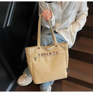 Detail view of beige canvas tote with side pocket and TAOCAITU lettering print