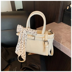Detail of cream square handbag with polka dot scarf and metallic buckle strap