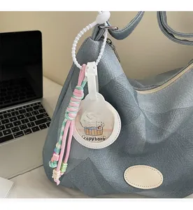 Gros plan d'un bijou de sac Capybara avec une corde tissée rose et verte sur un sac