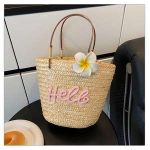 Detailansicht der Strohtasche mit Hello-Stickerei und weißer Frangipani-Blüten-Verzierung