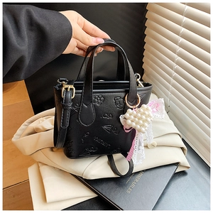Detail of black embossed PU leather bucket bag with 3D floral icons and pearl heart charm