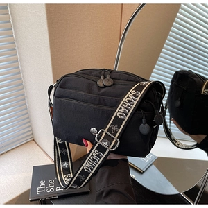 Détail du sac bandoulière en nylon noir avec sangle florale et multiples poches zippées