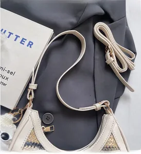 Detail of straw woven shoulder bag with cream leather trim and plush pompom charm