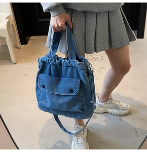 Detail der blauen Denim-Umhängetasche mit Kordelzug, Vordertasche und verstellbarem Riemen
