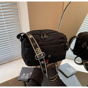 Détail du sac bandoulière en nylon noir avec compartiments zippés et sangle jacquard