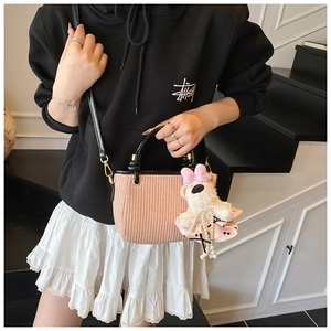 Détail du sac seau rose tressé avec poignées en cuir noir et charm ours mignon