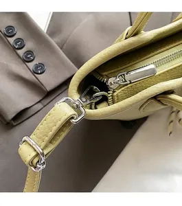 Détail de la fermeture éclair argentée et cuir grainé sur un sac seau vert moutarde