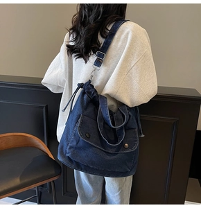 Blaue Denim-Tragetasche mit verstellbarem Gurt und geknöpfter Tasche am Modell gezeigt