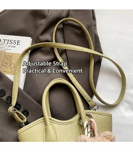 Détail du sac seau vert clair texture litchi avec bandoulière réglable et porte-clés