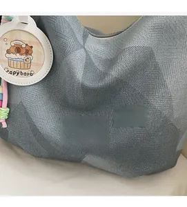 Détail d'un sac cabas tissé gris avec écusson Banatu et breloque capybara