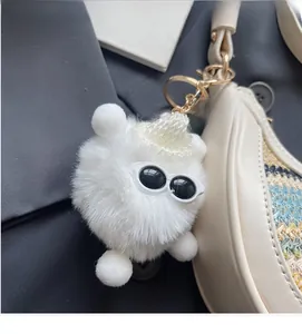 Detail of creative white monster keychain with mini sunglasses on a beige straw bag