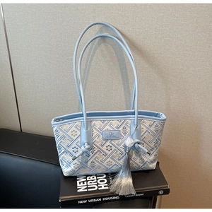 Detail der blauen Jacquard-Handtasche mit DM-Logo und langem grauem Quasten-Anhänger