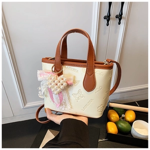 Detail of embossed leather handbag with butterfly patterns and pearl heart charm