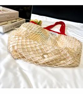 Detailed close-up of cream woven mesh handbag featuring vibrant red handles and cotton lining