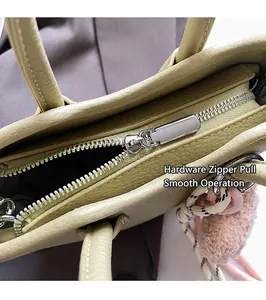 Détail de la fermeture éclair argentée sur le sac en cuir vert clair avec breloque rose