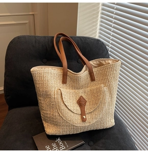 Detail of woven straw tote bag with brown leather handles and decorative front pocket