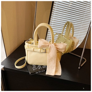 Detail of yellow pebbled leather handbag featuring an elegant polka dot scarf and buckle