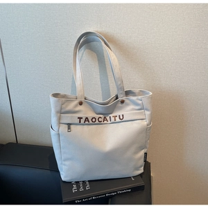 Close-up of canvas tote bag with metal buckles and external zipper pocket on leather sofa
