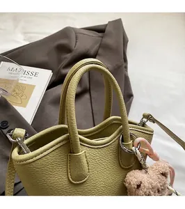 Détail du sac seau vert clair à texture litchi avec corde tressée et breloque ours